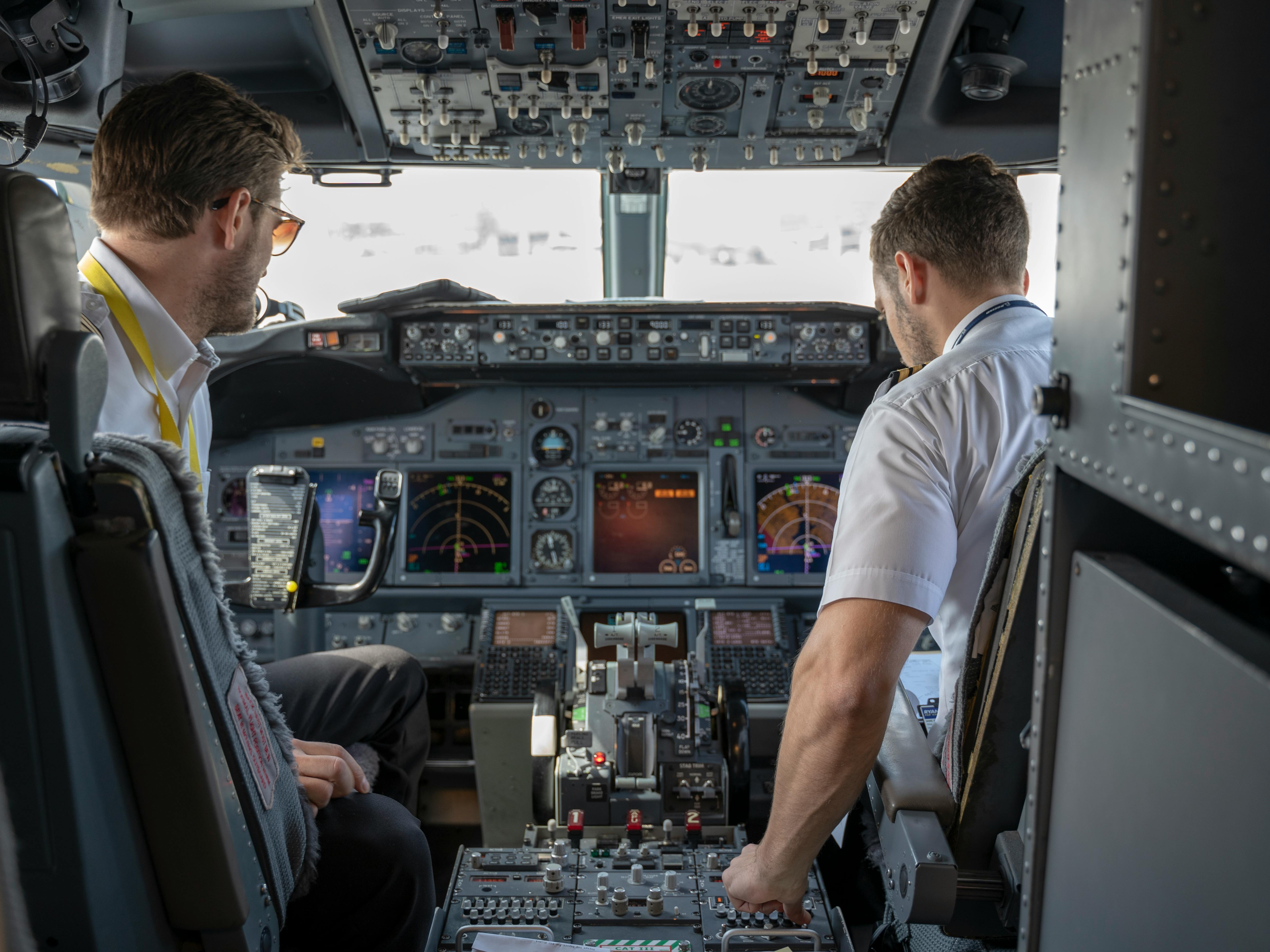 Two Pilots Sitting Inside Plane. Photo by Rafael Cosquiere.
